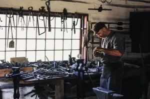 Nowoczesny stalowy grill gazowy na tarasie, z piekącymi się stekami i warzywami, na tle ogrodu w wieczornym świetle.
