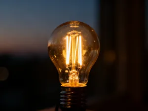 Nowoczesna lampa rzuca ciepłe światło na neutralną ścianę, tworząc kontrast z chłodnym cieniem i ukazując zmienność koloru.